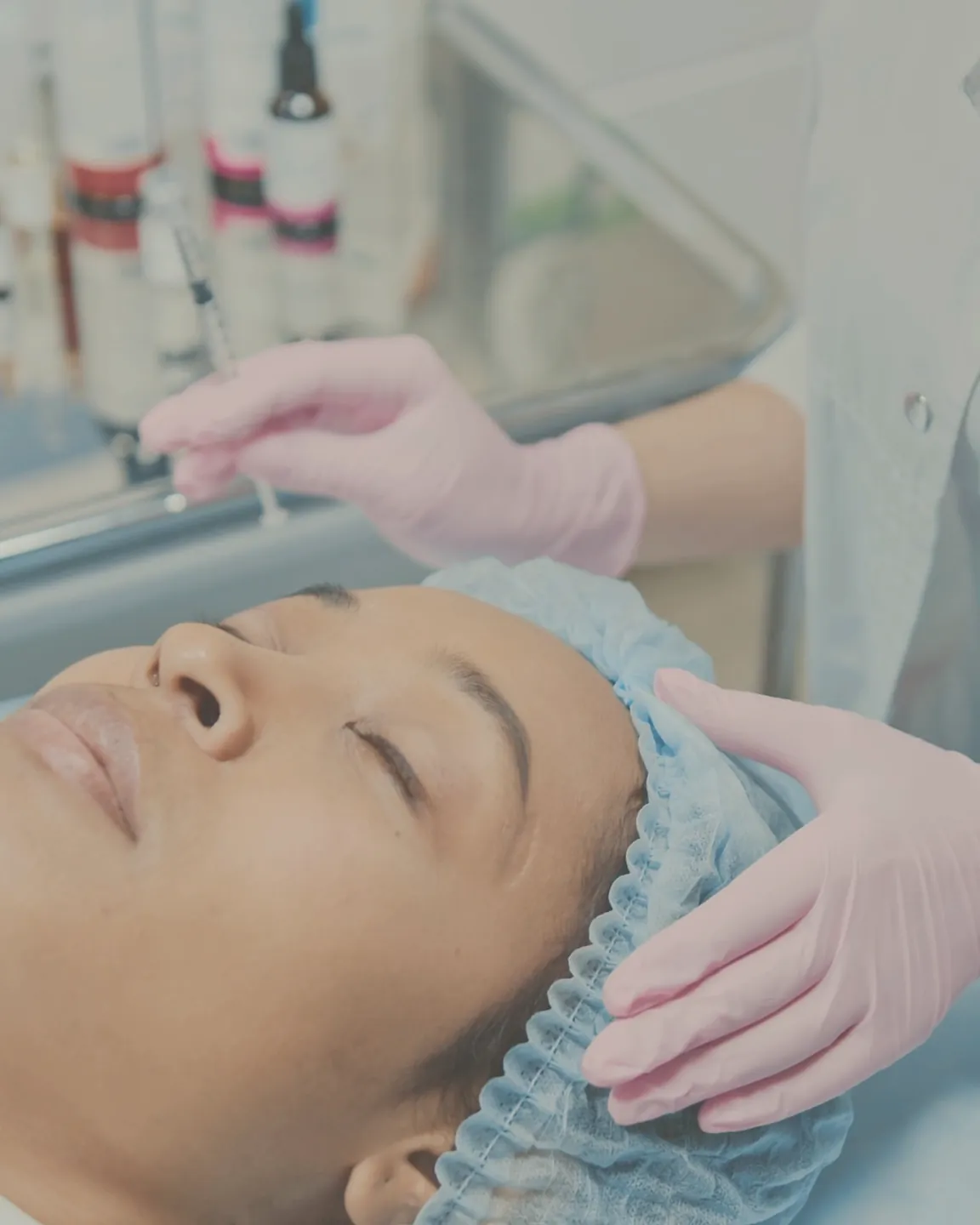 A gloved practitioner during treatment, with the patient relaxed and her eyes closed on the treatment bed